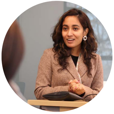 Sanju Koirala, middle easter woman wearing a suit and speaking at podium in front of an audience. 
